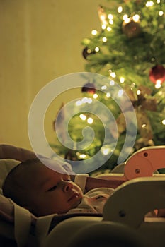 A small child lies under the Christmas tree.