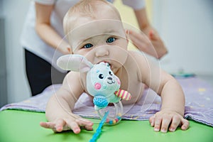 A small child lying on his stomach gets a massage in a massage room. He has a toy in his mouth