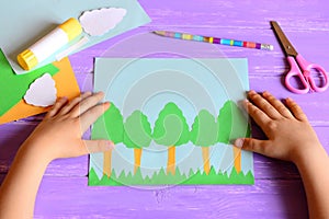 Small child made a Earth day card. Materials and tools for create a simple kids crafts. Children`s hands on a desktop