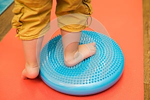 Little kid massages his feet while standing on the rug