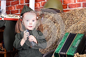 Small child in military uniform on the holiday of victory; wartime decorations. Country style