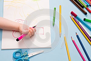 a small child painstakingly draws with a pink felt-tip pen in an album
