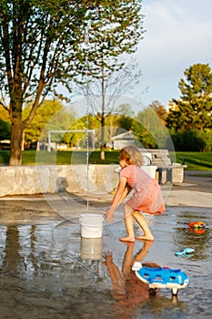Small child at playground in park playing with water and toys. Little girl at splash pad in summer