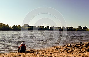 small child is playing alone on the beach. Young boy unattended by the lake