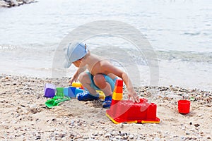 Small child is playing with sand on the beach