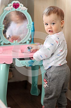 a small child plays in front of a toy mirror in the nursery