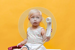 A small child plays with an old corded telephone