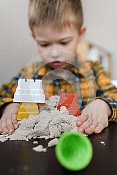 A small child plays in the sandbox at home. Boy makes sand molds