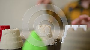 A small child plays in the sandbox at home. Boy makes sand molds