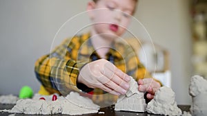 A small child plays in the sandbox at home. Boy makes sand molds