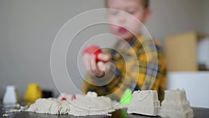 A small child plays in the sandbox at home. Boy makes sand molds