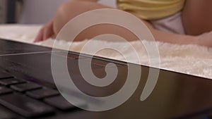 A small child presses a finger on the button on the laptop keyboard, close-up, baby and computer, education