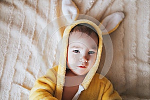 A small child with a rabbit costume. Lying on bad