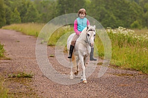 Small child riding on a white horse on the road Outdoors