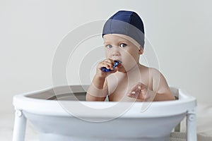 A small child rushes his teeth while sitting in the bathroom
