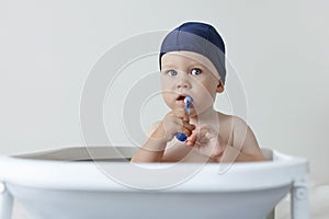 A small child rushes his teeth while sitting in the bathroom