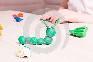 a small child sculpts from plasticine, a wooden light table