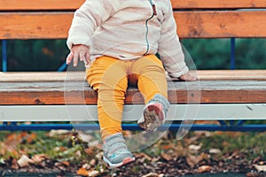 A small child is sitting alone on a bench, legs in close-up. The concept of lost children and an orphanage