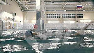 a small child is sitting on the edge of the pool in a life jacket and with a trainer's whistle around his neck. He