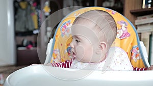 Small child sitting on the highchair and fidgets.