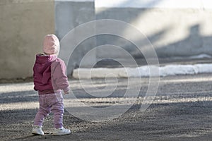 Small child stands alone on empty street. Girl in autumn clothes itself in the street. Safety of children