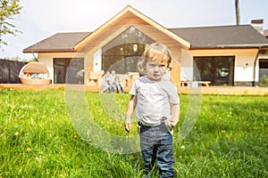 Small child stands on the background of the house. young family move to a new country house. moving day.