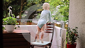 a small child stands on a chair on the balcony. danger of falling from a height. fall out of the window