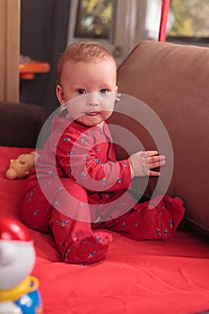 A small child stands and holds the edge of the bed or playpen in the nursery, happy and happy smiling baby, the concept of child d