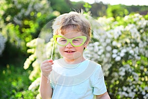 Small child with summer party glasses. Childhood happiness. Childrens day. Little boy child in green forest. spring