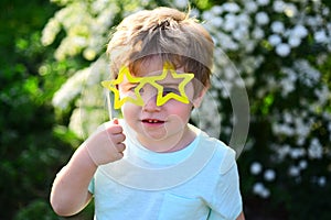 Small child with summer party glasses. Little boy child in green forest. spring holiday. Sunny weather. Happy kid in