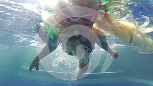 A small child swims in a pool underwater. Girl learns to swim in the pool wearing goggles for diving.