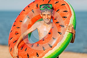 Small child teen boy in swimming glasses, with an inflatable swimming circle on the beach . Summer holiday