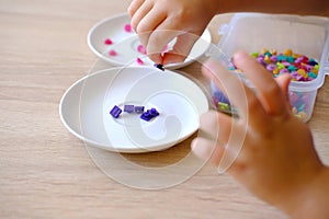 small child, toddler sorts small plastic chips by color, kid's fingers closeup, development fine motor skills, tactile