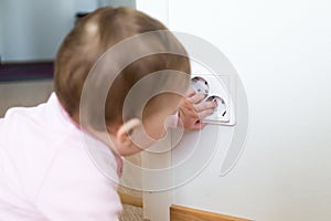 Small child touches an electrical outlet at home. Safety of children