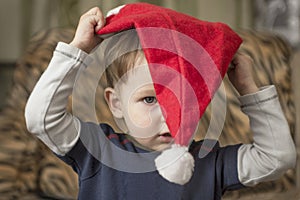 A small child is trying to put on a Santa Claus hat