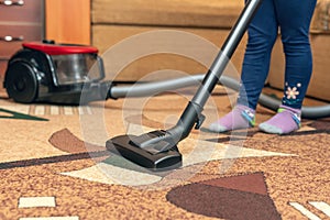 A small child vacuums a carpet with a vacuum cleaner