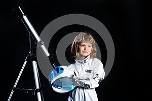 Small child wants to fly an in space, kid boy with telescope wearing an astronaut helmet. Copy space. Success, creative