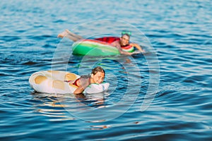 Small children boy and girl, swimming in the sea with inflatable circles, having fun on the beach during the summer holidays