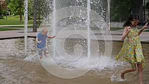 Small children have fun in the ground fountain in the summer.