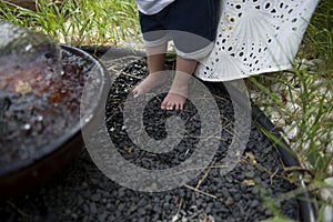 Small children's feet stand on small black decorative stones near the fountain