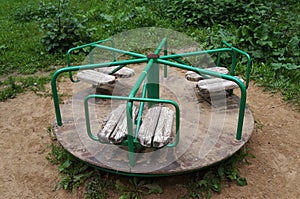 Small children`s old carousel in a courtyard. Green knobs, shabby wooden seats, floor with peeling paint