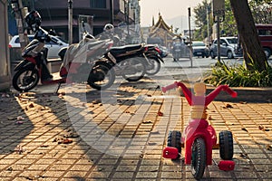 Small children tree-wheeled bicycle standing in front of motorbikes and scooters. photo