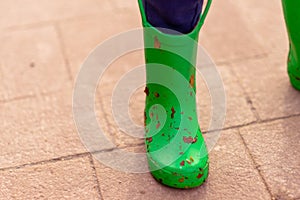 Small childs green welly covered in dirt and leaves