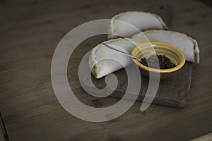 Small chopping board displaying typical food from Portugal and South America, Chicken and Beef Empanada favored with spicy and