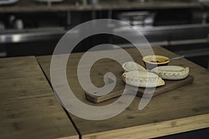 Small chopping board displaying typical food from Portugal and South America, Chicken and Beef Empanada favored with spicy and