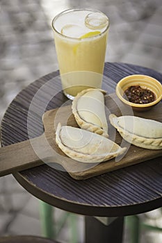 Small chopping board displaying typical food from Portugal and South America, Chicken and Beef Empanada favored with spicy and