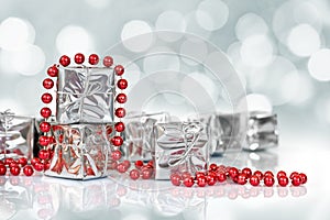 Small Christmas gifts in shiny silver paper and red tinsel beads