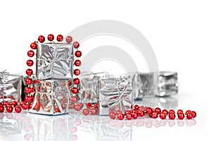 Small Christmas gifts in shiny silver paper and red tinsel beads ornament