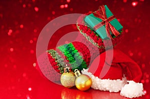 Small Christmas stocking and Santa hat on red sparkle background