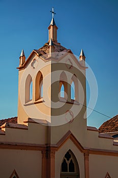 Small church facade and belfry with sunlight on one side and shadow on the other, at sunset in SÃ£o Manuel.